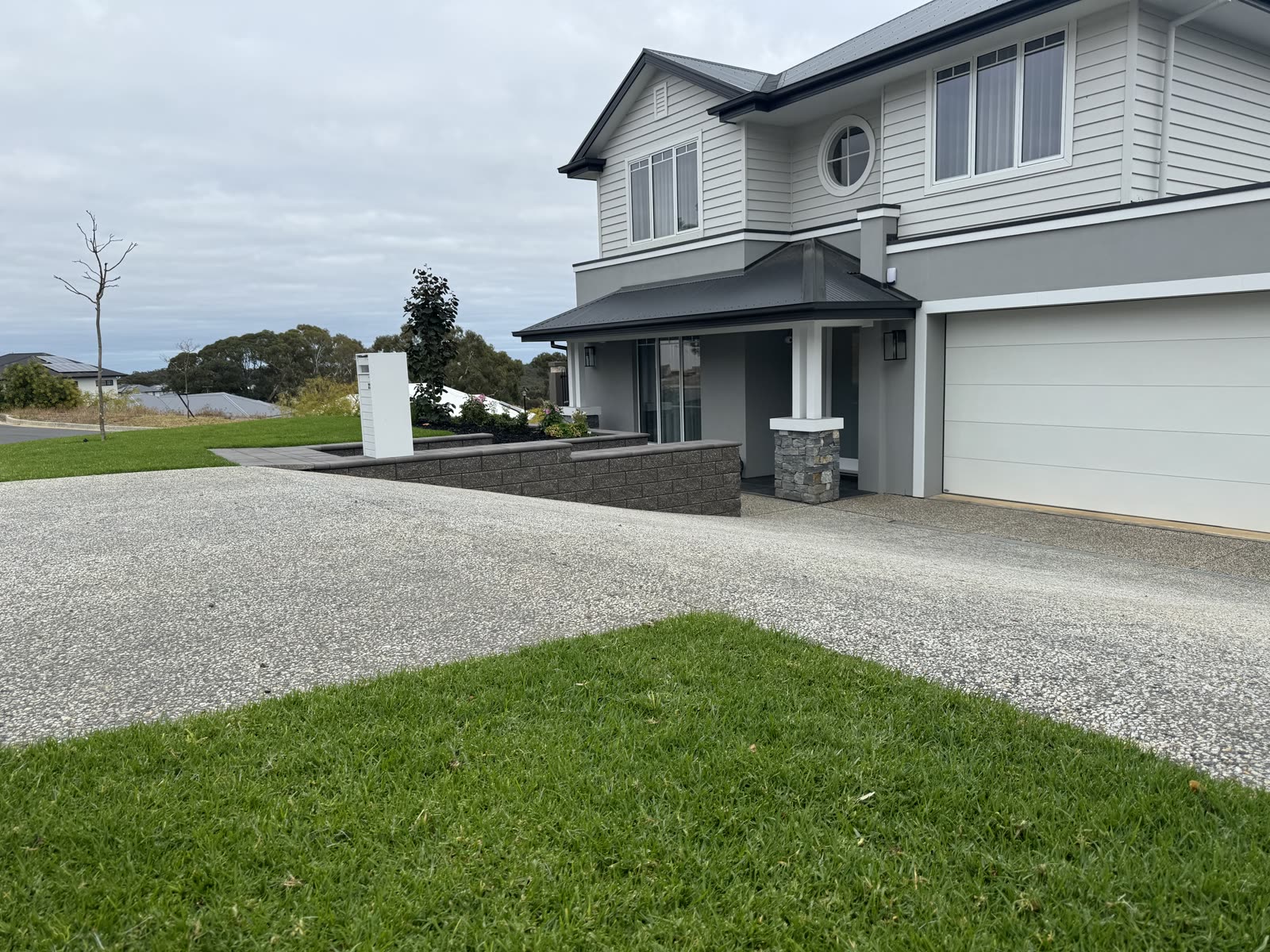 Front garden in Craigburn Farm with an exposed-aggregate driveway, new turf and a rendered stone-clad retaining wall along the letterbox