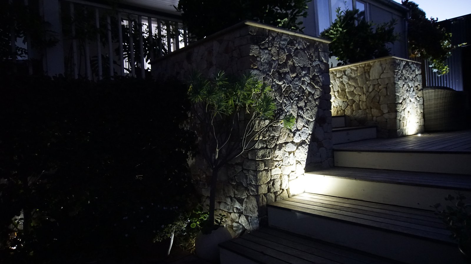 Stone-clad retaining wall and steps lit with low-voltage spotlights at dusk in McLaren Vale, highlighting the stonework texture