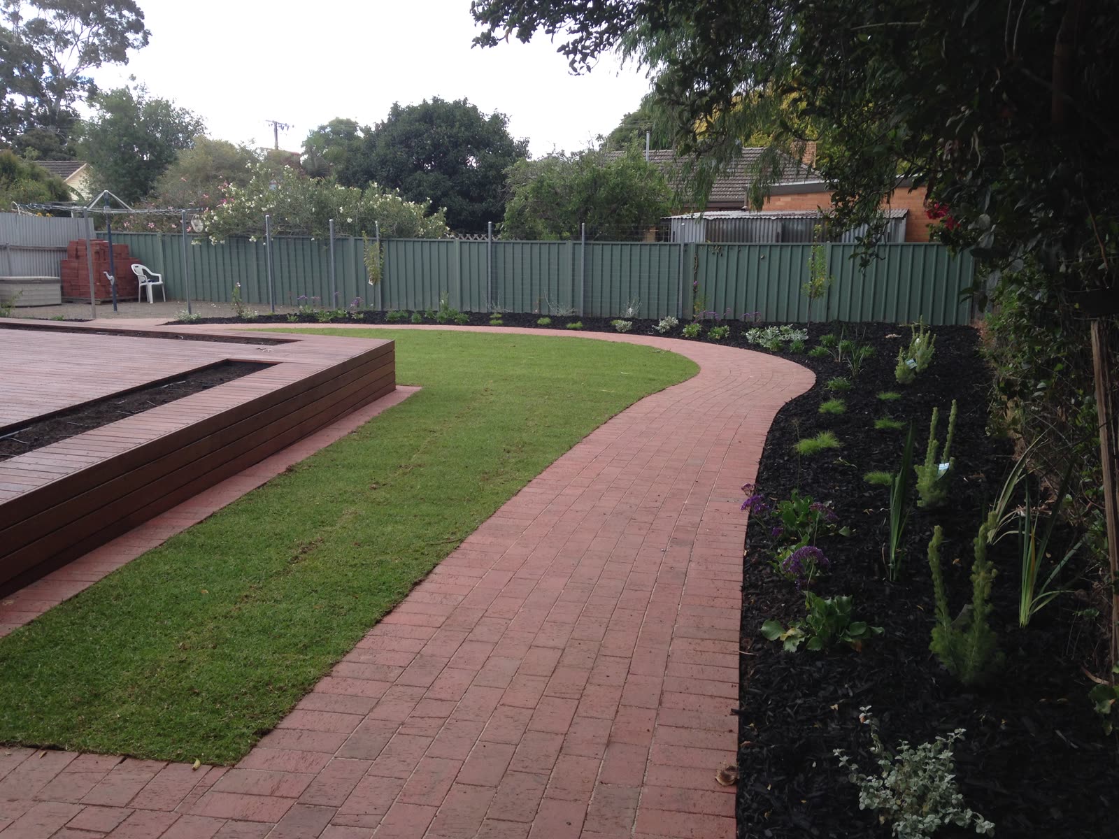 Curved brick-paved path around a new lawn and low-maintenance garden bed alongside a hardwood deck in Oaklands Park